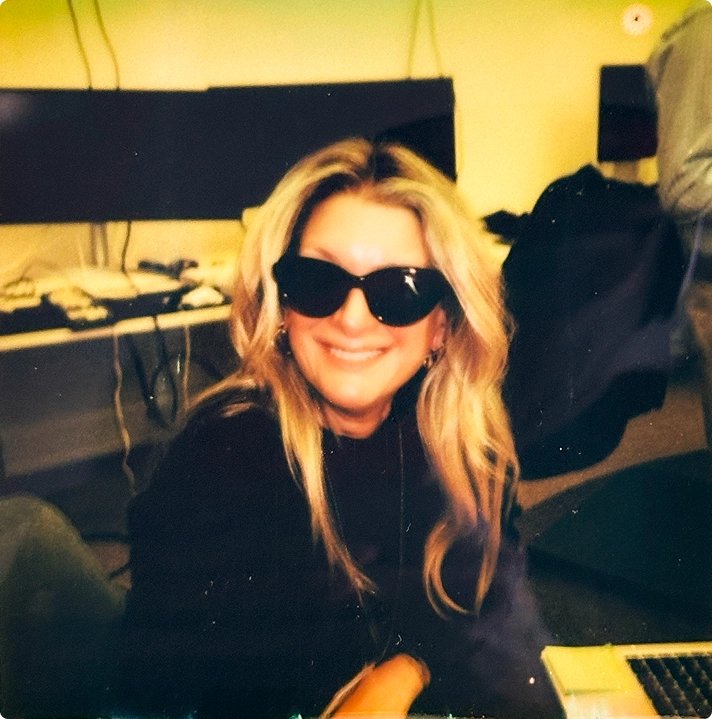 Team member smiling at a cluttered studio desk