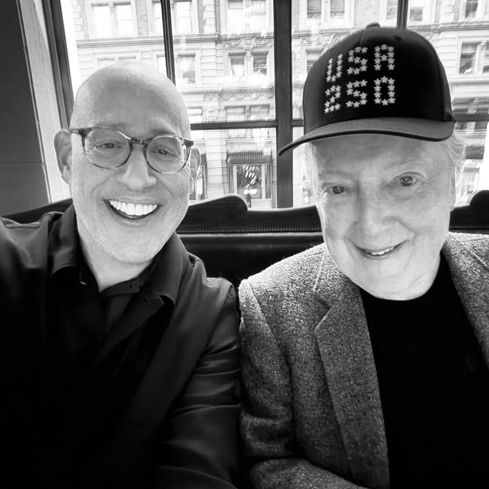 Peter Arnell and Lance Wyman seated together, Lance Wyman wearing a USA 250 hat