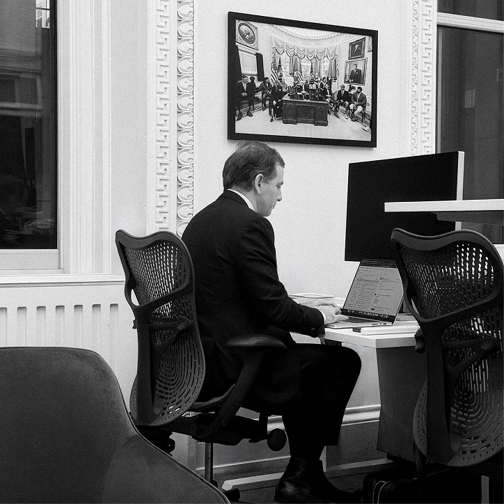 Team member working at a desk beneath a historic cabinet photograph