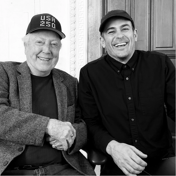 Lance Wyman and a team member seated and holding hands