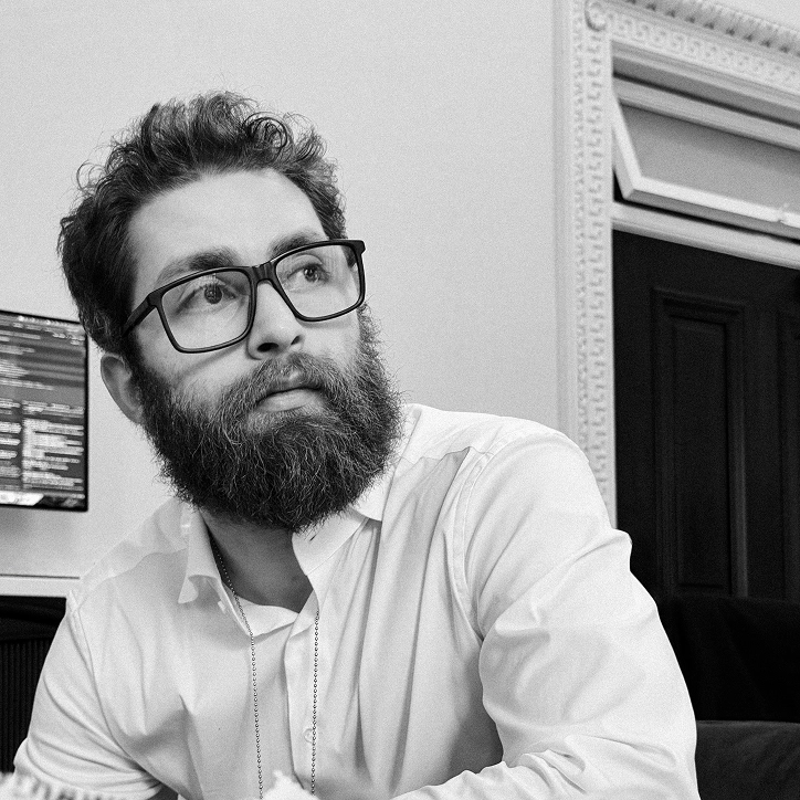 Bearded engineer seated at his desk in a white shirt