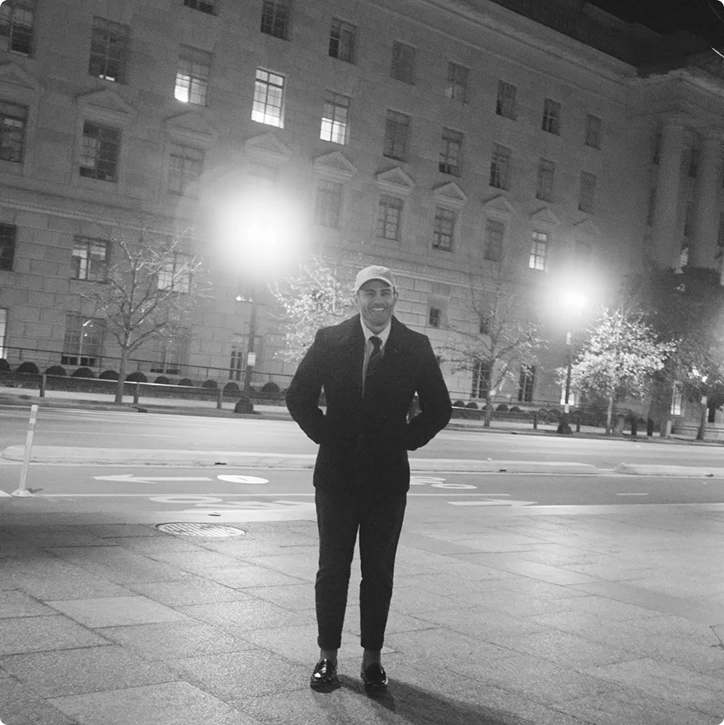 Young man in a suit standing on a plaza at night