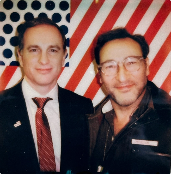 Two team members posing in front of a patriotic red, white, and blue backdrop